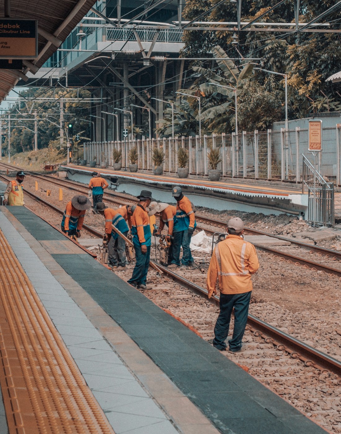 Railway workers repairing train tracks at a station; illustrative stock photograph